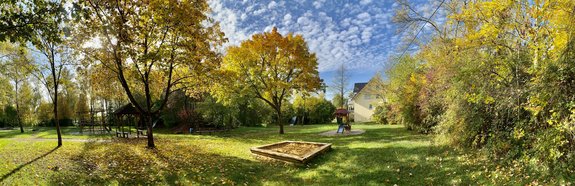 Blick auf den Kinderspielplatz im Sepp-Steinberger-Park in Reisbach. Der Spielplatz liegt auf einer grünen Wiese, umgeben von vielen Bäumen.